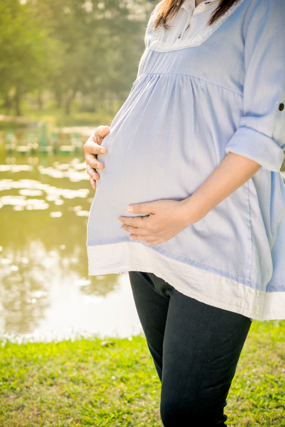 Young pregnant woman relaxing in park outdoors, healthy twin pregnancy